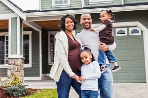 family smiling at camera outside home