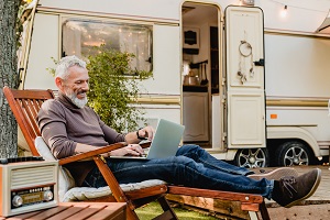 man sitting outside rv on laptop